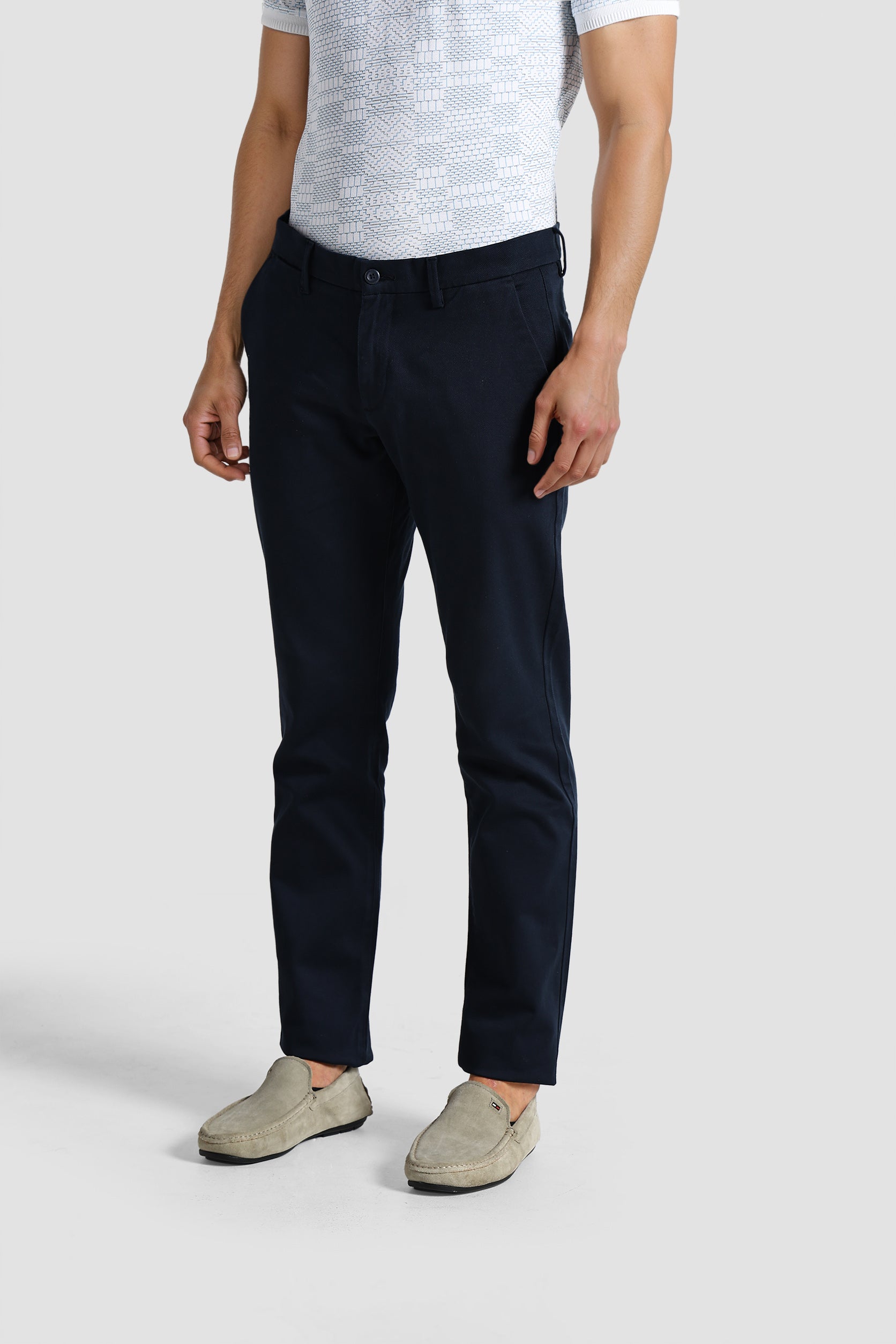 Person wearing navy pants and a light gray shirt on a white background