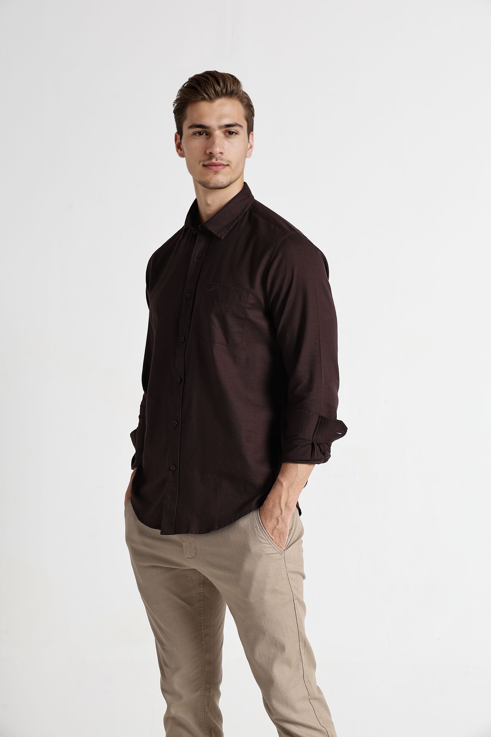 Man wearing a dark brown shirt and beige pants on a white background