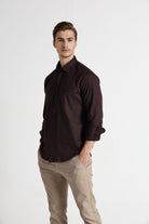 Man wearing a dark brown shirt and beige pants on a white background