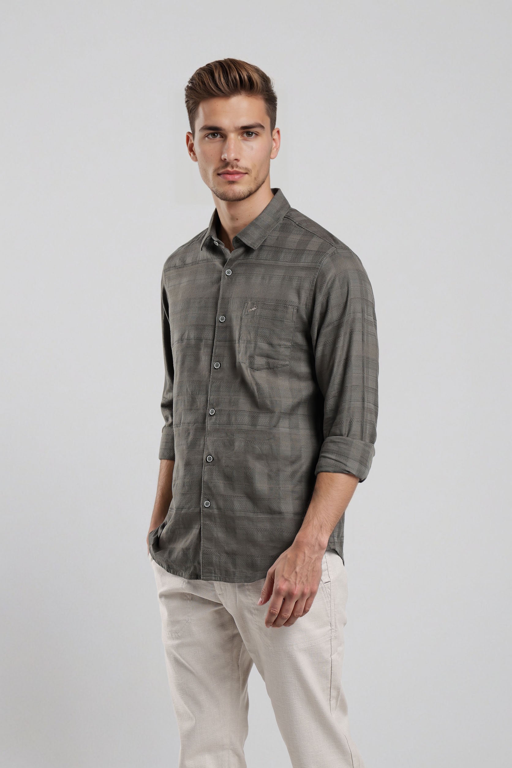 Man wearing a gray plaid shirt and light-colored pants on a white background