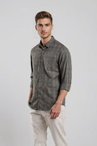 Man wearing a gray plaid shirt and light-colored pants on a white background