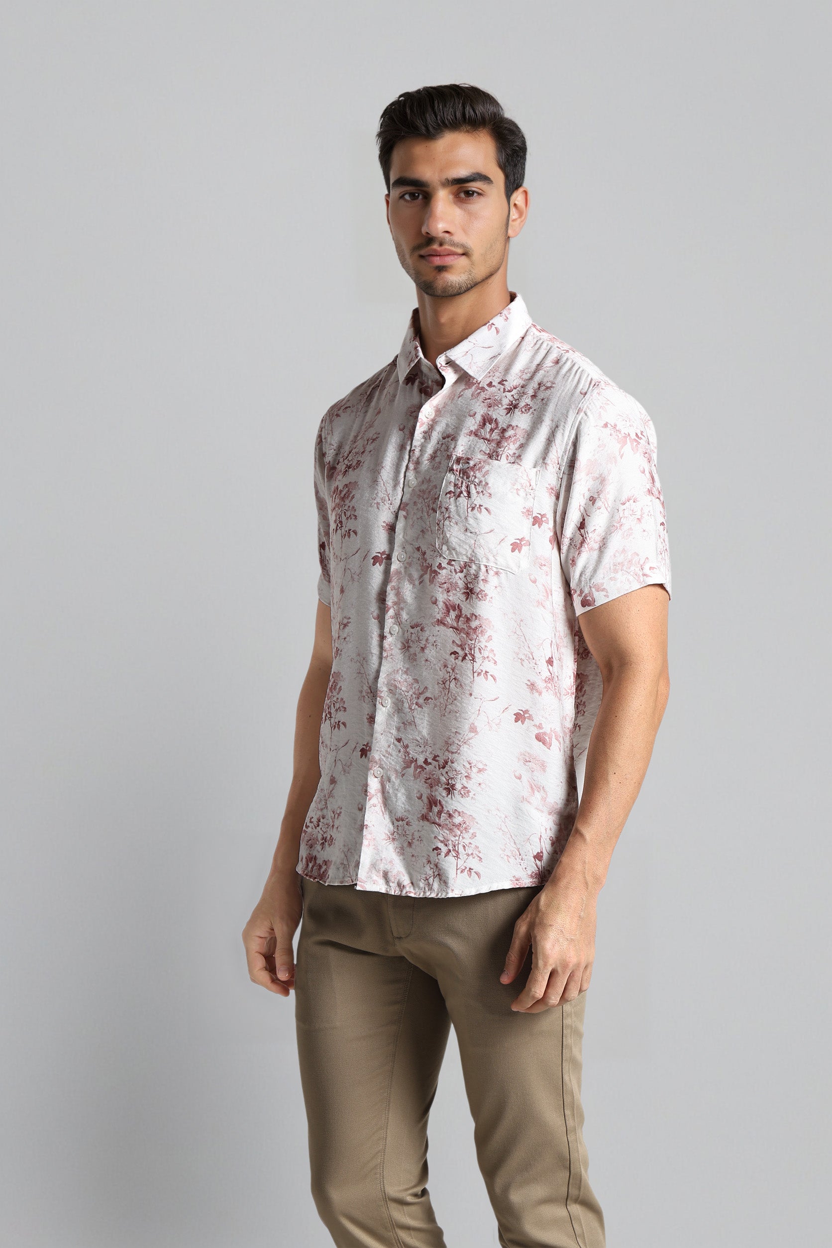 Man wearing a patterned shirt and beige pants on a gray background