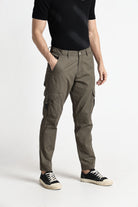 Person wearing brown cargo pants and black shoes on a white background