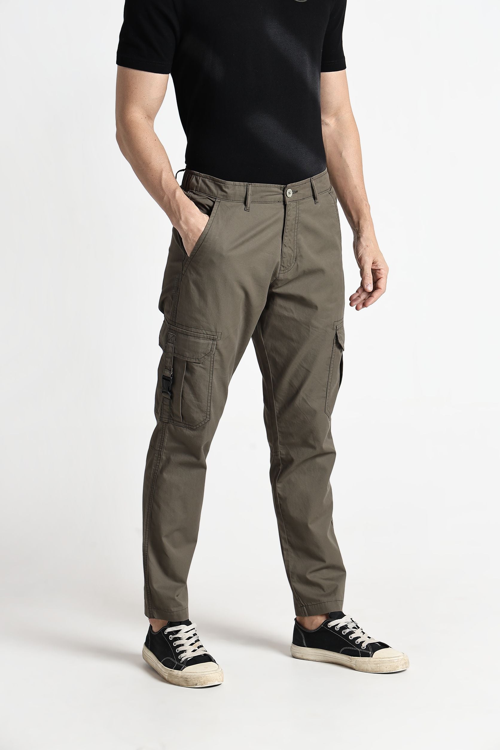 Person wearing brown cargo pants and black shoes on a white background