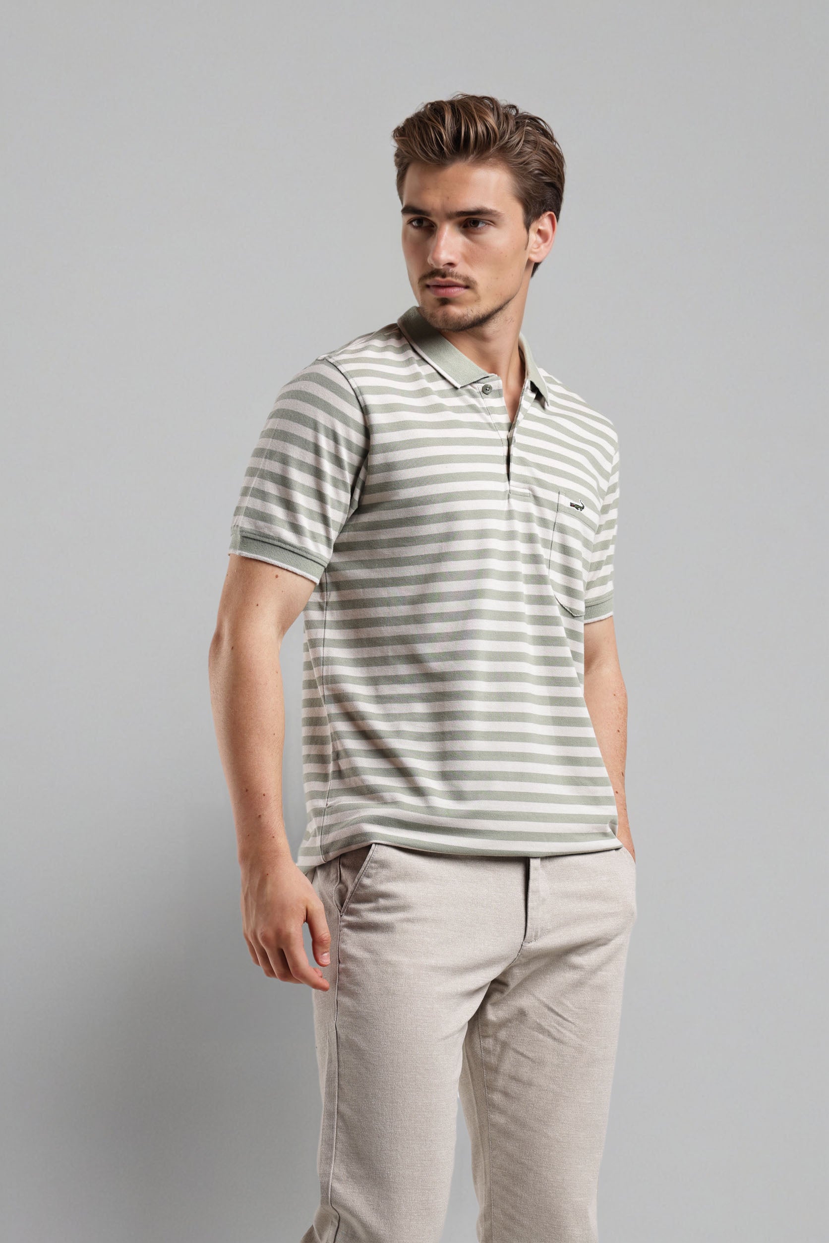 Man wearing a striped polo shirt and beige pants against a gray background