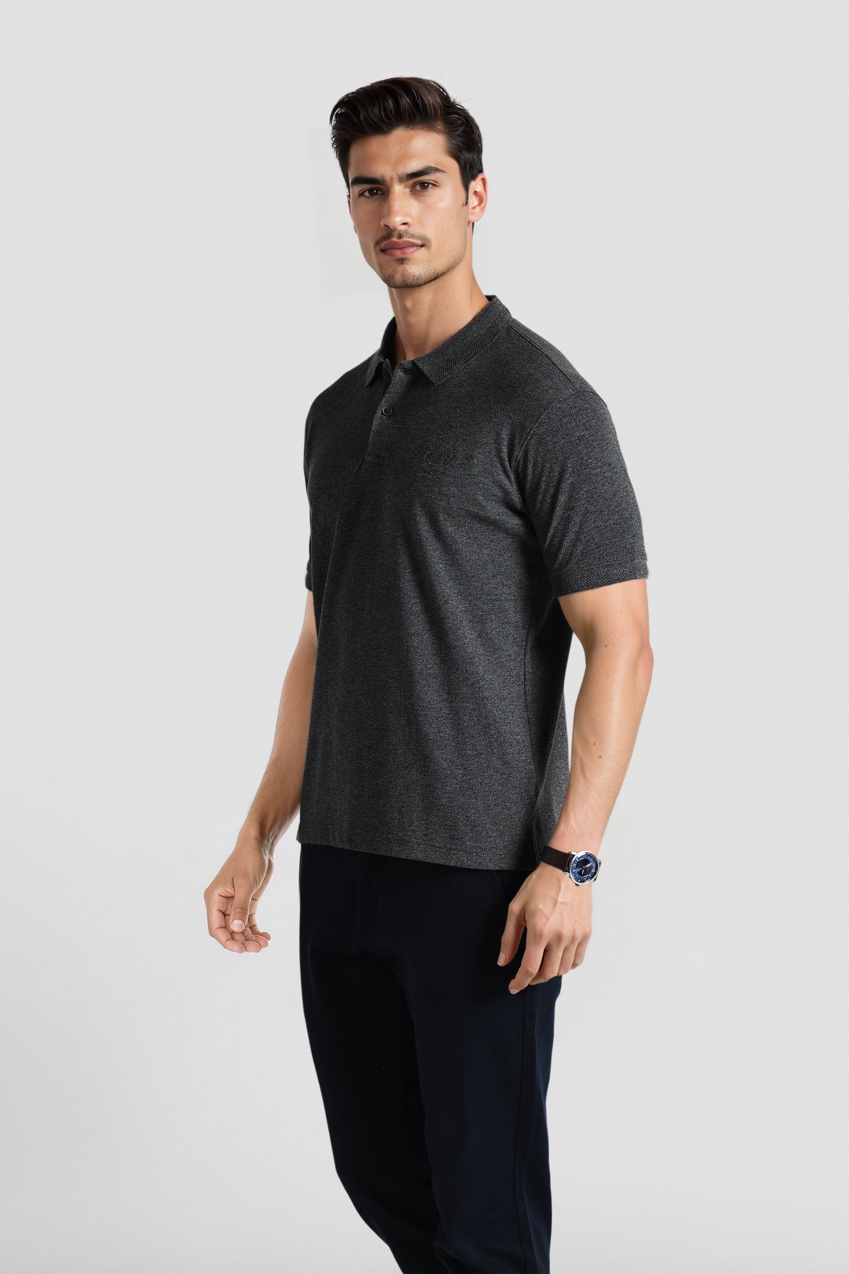 Man wearing a dark gray polo shirt and black pants on a light gray background