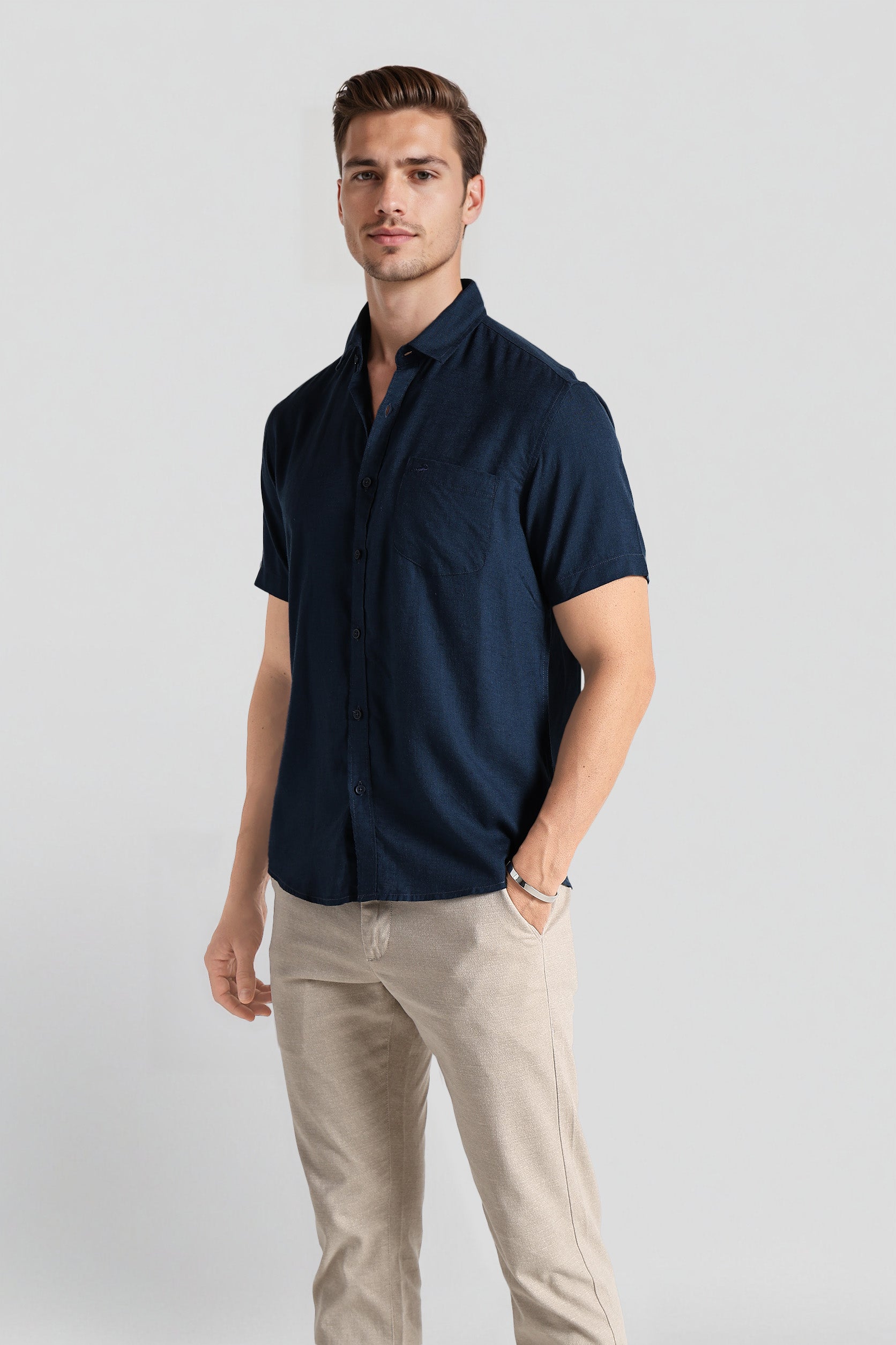 Man wearing a navy blue shirt and beige pants on a light gray background