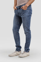 Person wearing blue jeans and white sneakers on a white background