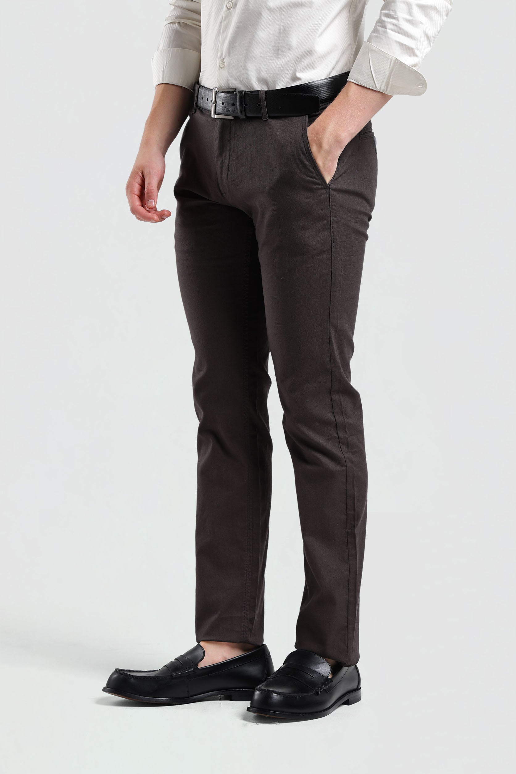 Person wearing brown dress pants with a white shirt and black loafers on a light gray background