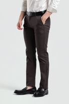 Person wearing brown dress pants with a white shirt and black loafers on a light gray background