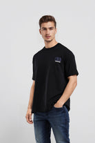 Man wearing a black t-shirt with a logo on a light gray background