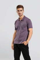 Man wearing a purple polo shirt and black pants on a light gray background