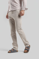 Person wearing light-colored pants and sandals on a plain background