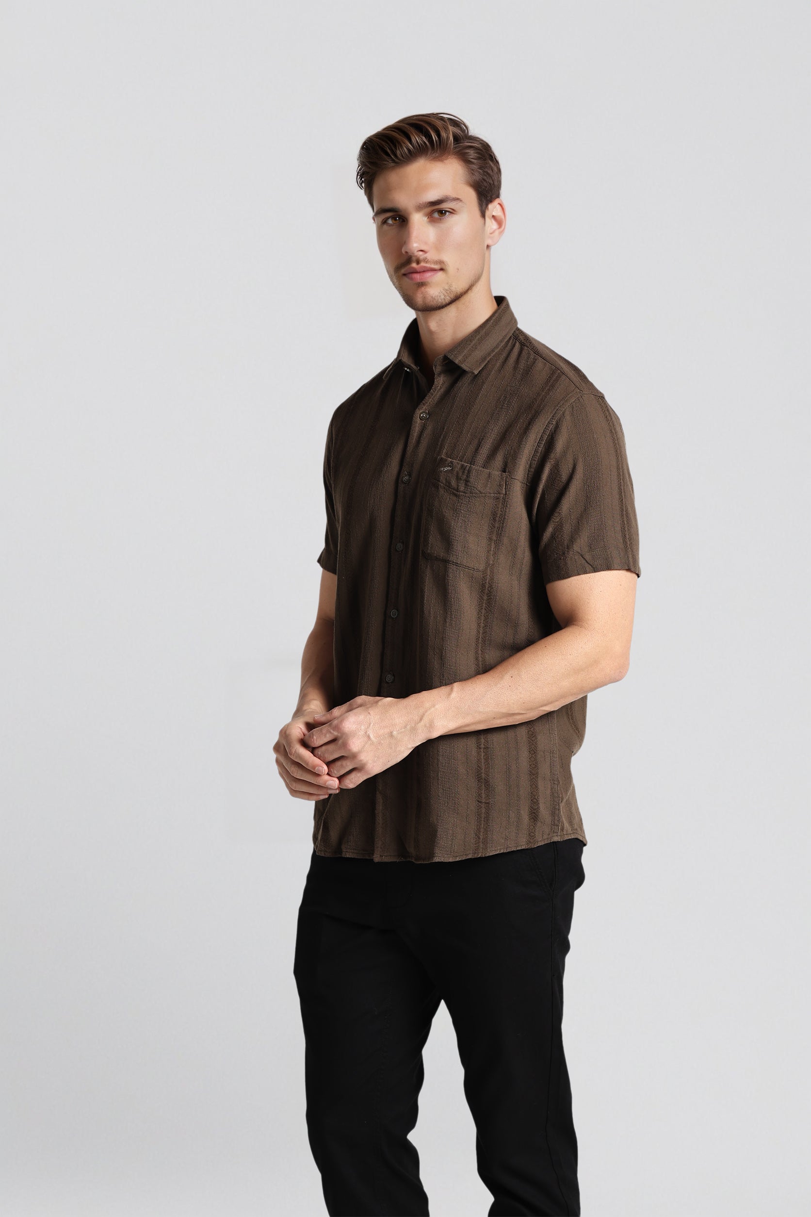 Man wearing a brown short-sleeve shirt on a light gray background