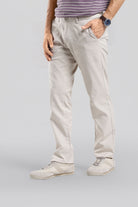 Person wearing light-colored pants and a striped shirt on a plain background