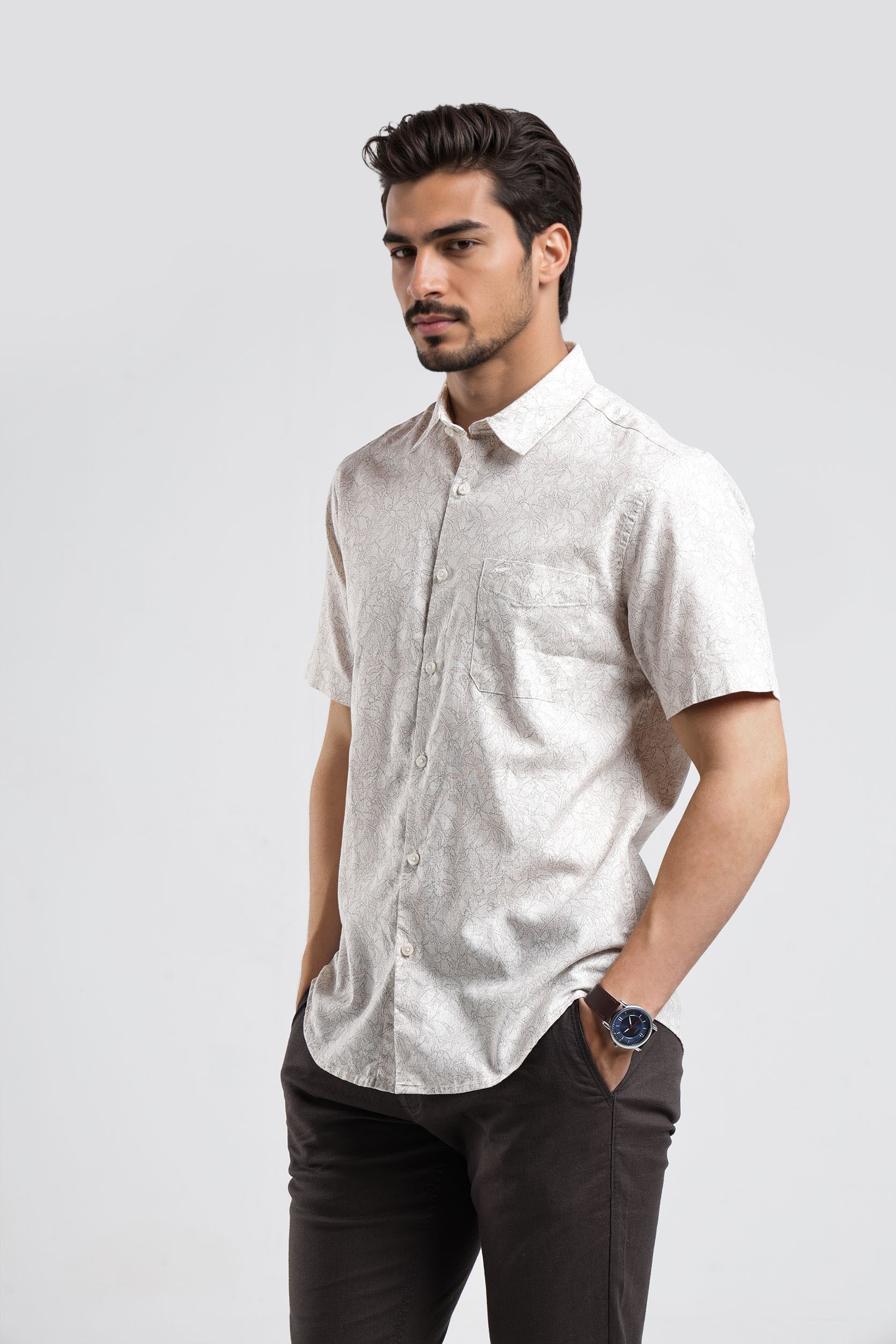 Man wearing a white short-sleeve shirt and dark pants on a light gray background