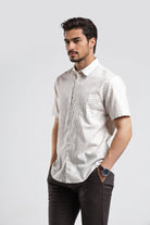 Man wearing a white short-sleeve shirt and dark pants on a light gray background