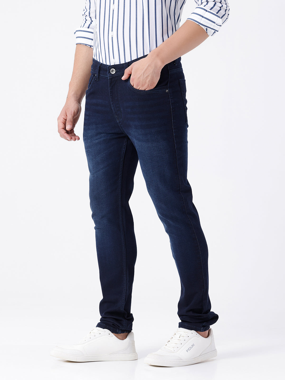 Man wearing a blue dark blue knit slim fit jeans with casual styling on a gray background