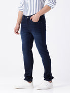 Man wearing a blue dark blue knit slim fit jeans with casual styling on a gray background