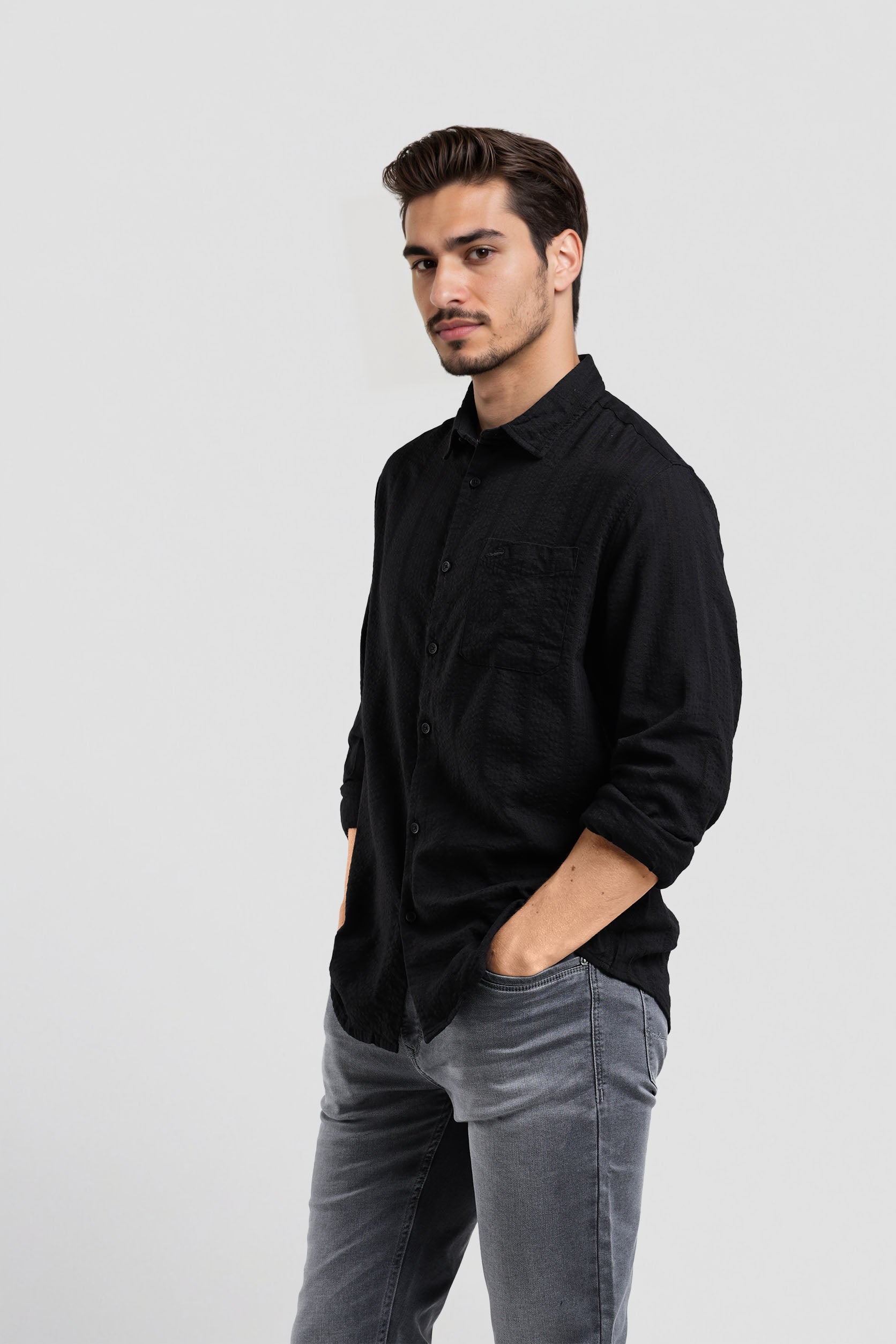 Man wearing a black shirt and gray pants on a white background