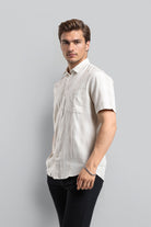 Man wearing a white short-sleeve shirt against a gray background