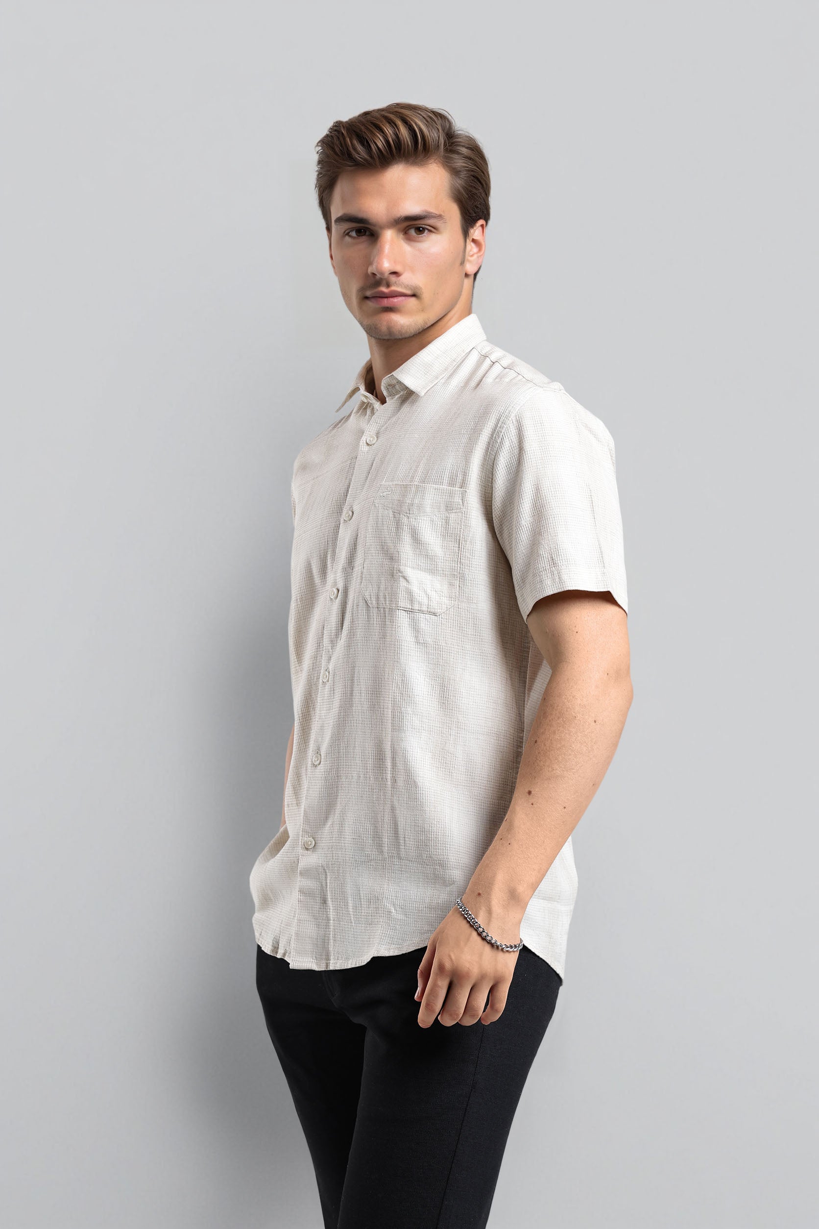 Man wearing a white short-sleeve shirt against a gray background