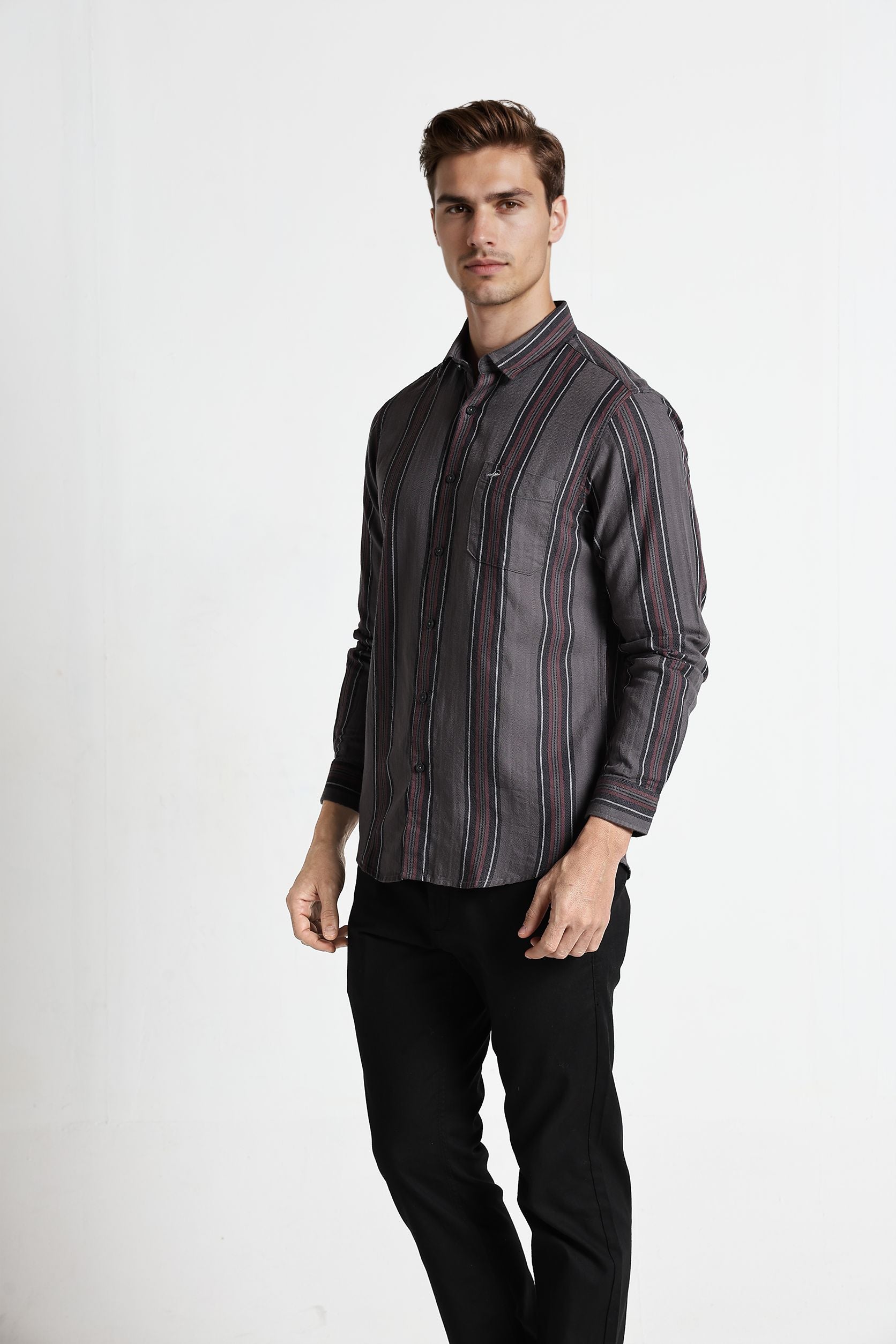 Man wearing a striped shirt and black pants on a white background