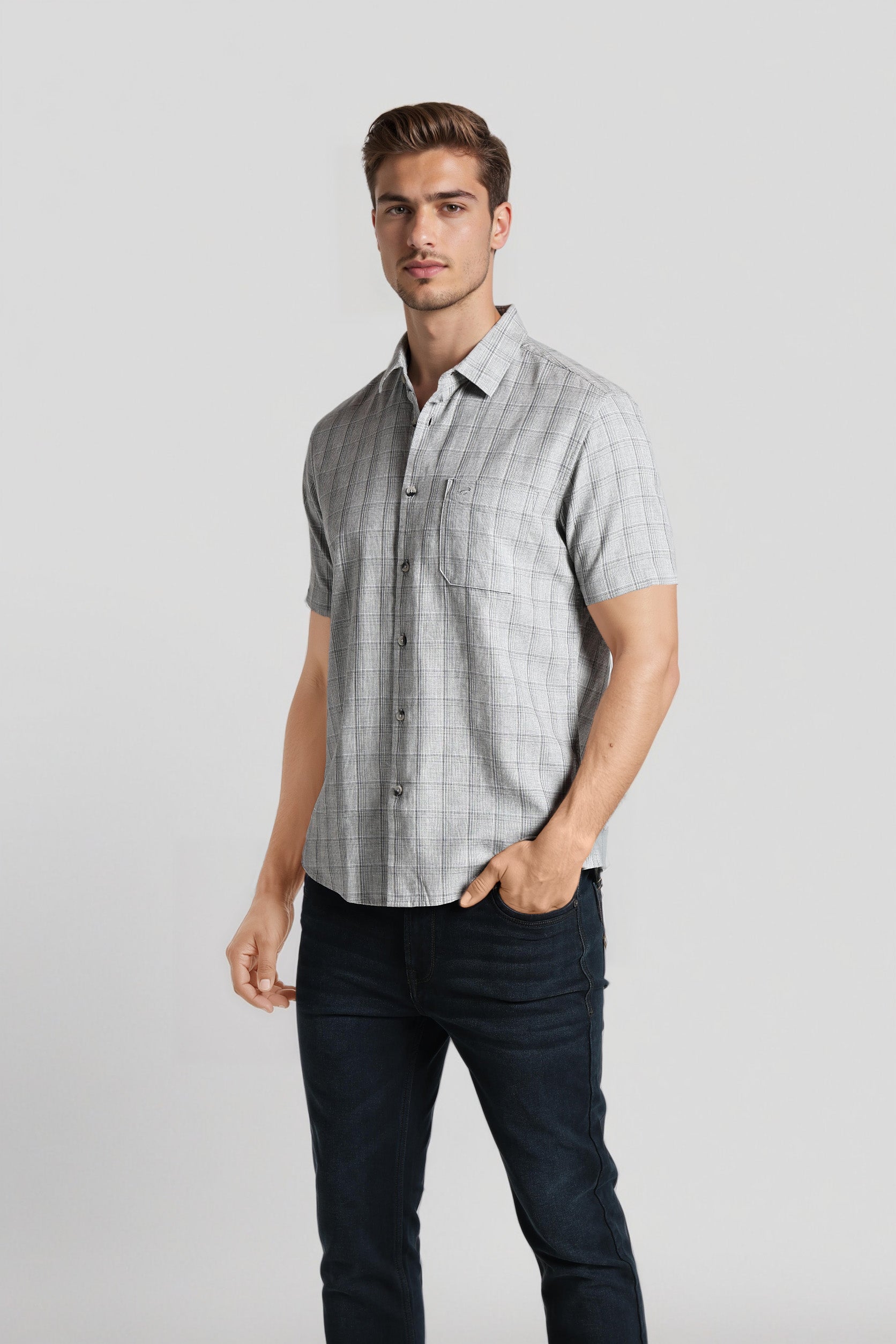 Man wearing a checkered shirt and dark pants on a light gray background