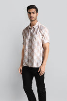 Man wearing a patterned shirt and black pants on a gray background