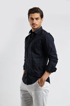 Man wearing a black shirt and white pants on a light gray background