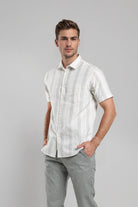 Man wearing a white striped shirt and gray pants on a gray background