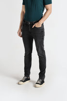 Person wearing black jeans and a green shirt on a white background