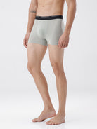 Person wearing light gray boxer briefs with a black waistband on a white background
