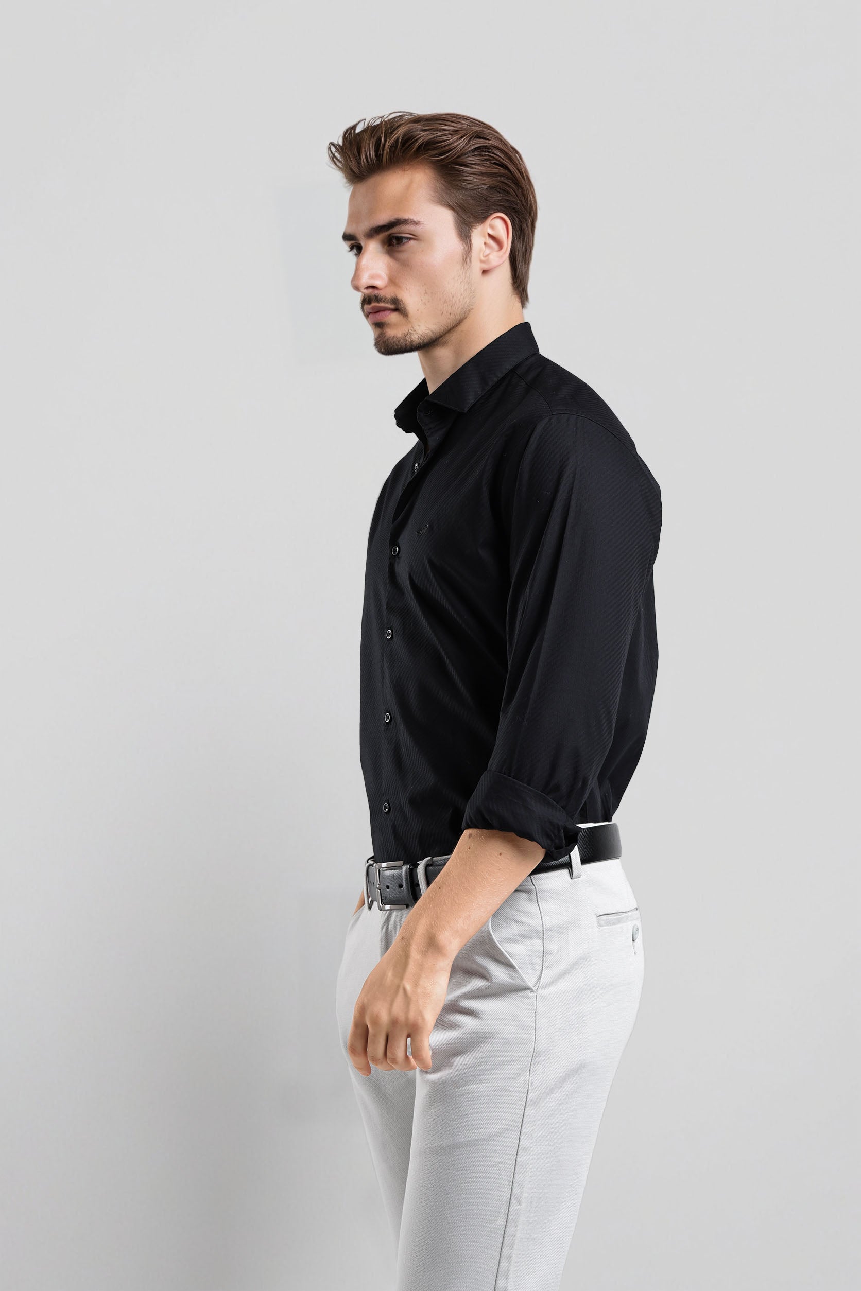Man wearing a black shirt and white pants on a gray background
