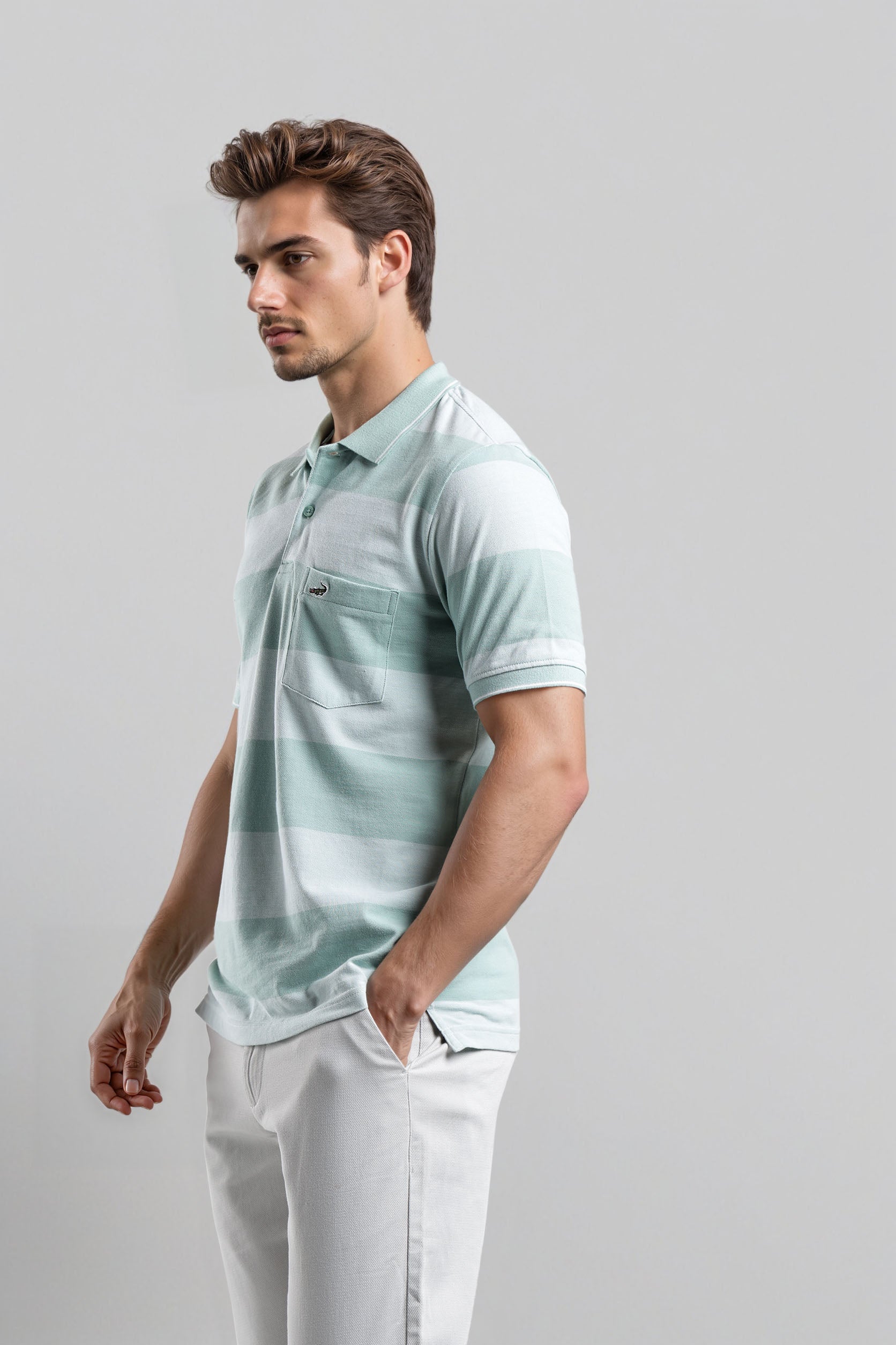 Man wearing a light green polo shirt and white pants on a gray background