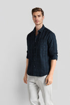 Man wearing a dark blue shirt and light gray pants on a white background