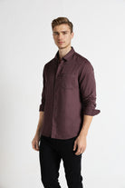 Man wearing a maroon button-up shirt and black pants on a white background