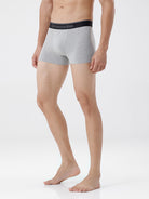Person wearing gray boxer briefs with a brand logo on a white background