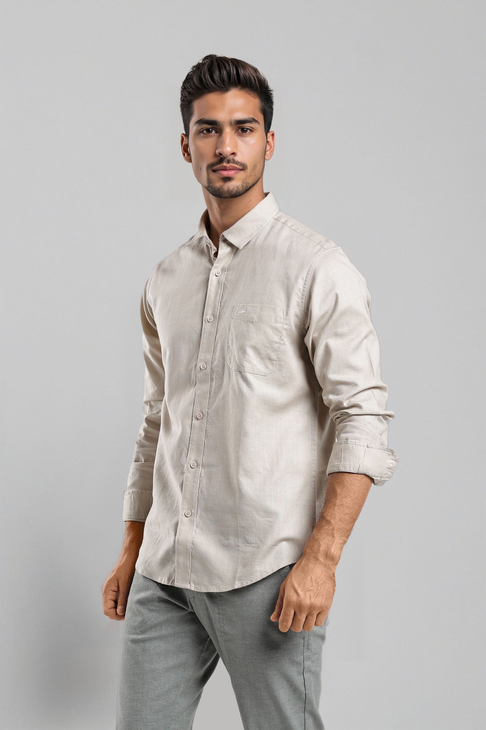 Man wearing a light-colored shirt and gray pants against a plain background