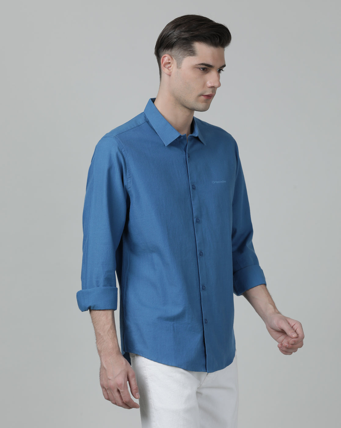 Man wearing a blue royal blue solid full sleeve linen shirt on a light gray background