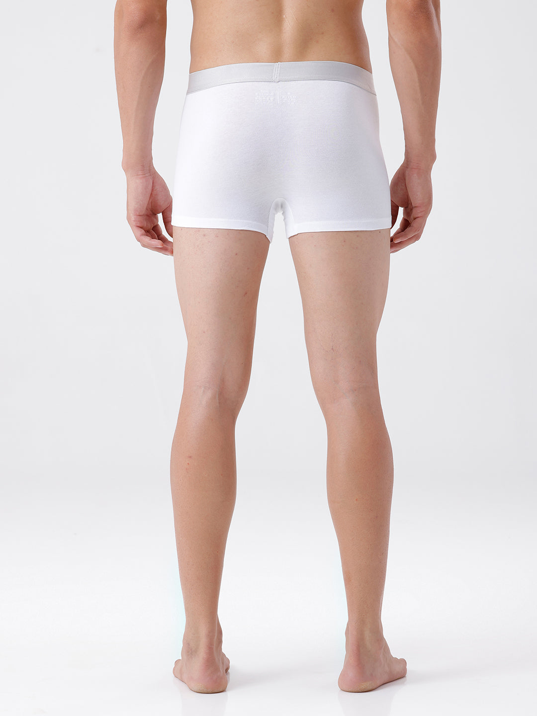 Person wearing a white boxer brief on a plain background