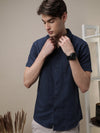 Man wearing a navy navy solid half sleeve linen shirt on a light gray background