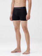 Person wearing black boxer briefs with a brand logo on a white background
