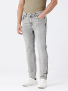 Man wearing a grey light grey knit slim fit jeans on a light gray background