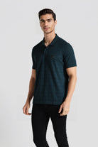 Man wearing a dark green polo shirt on a light gray background