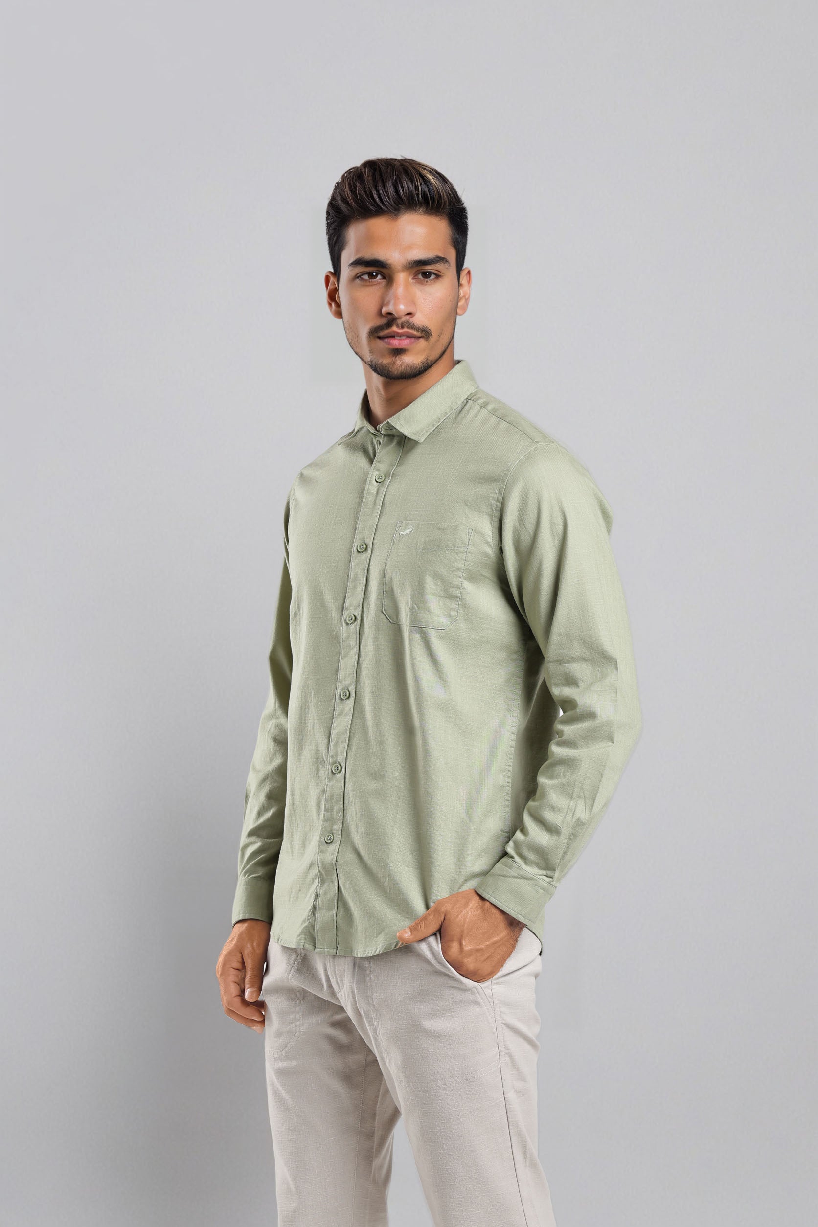 Man wearing a light green shirt and white pants against a gray background