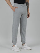 Person wearing gray sweatpants and white sneakers on a plain background