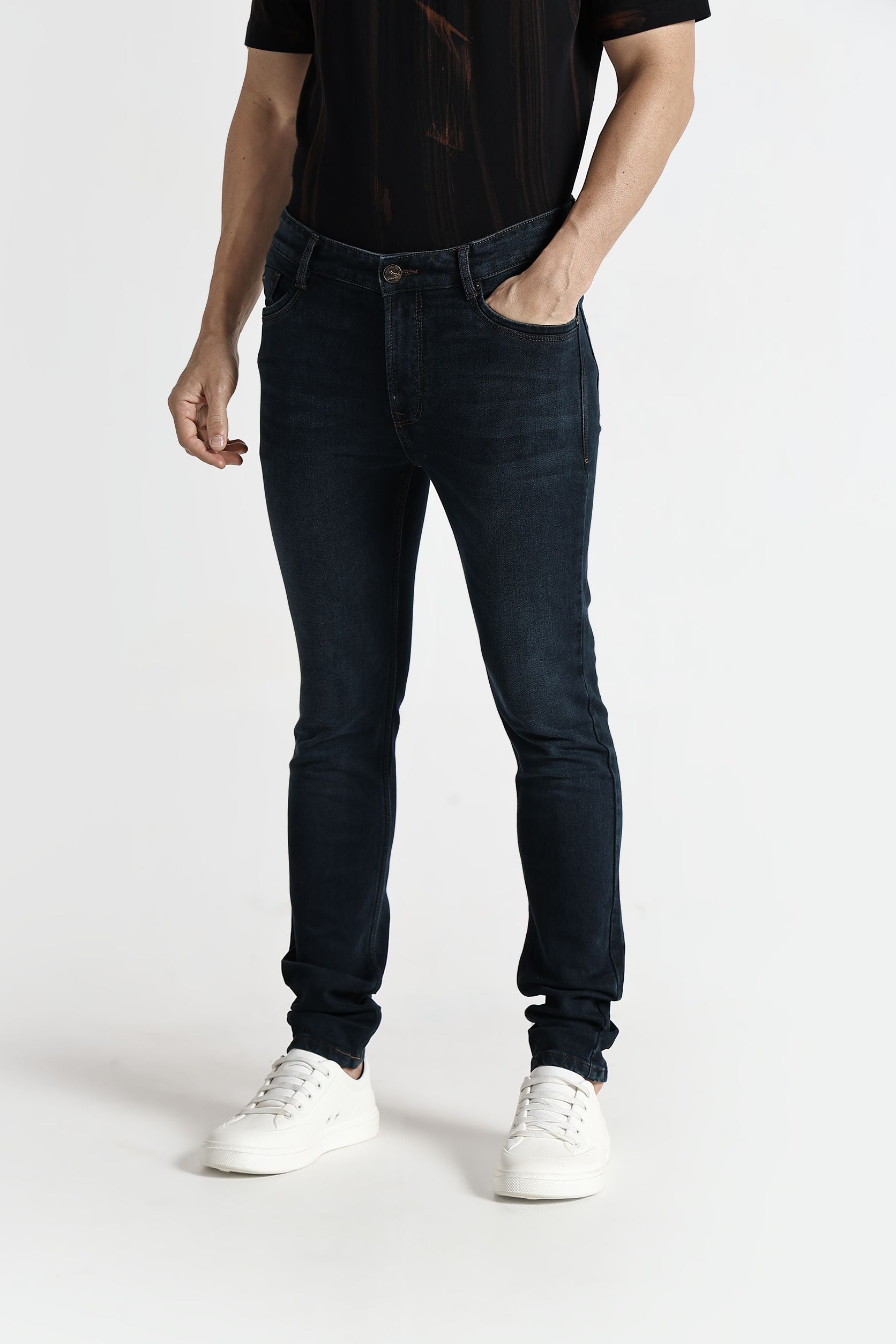 Person wearing dark jeans and white sneakers on a white background