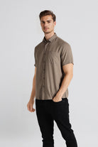 Man wearing a brown short-sleeve shirt and black pants on a white background