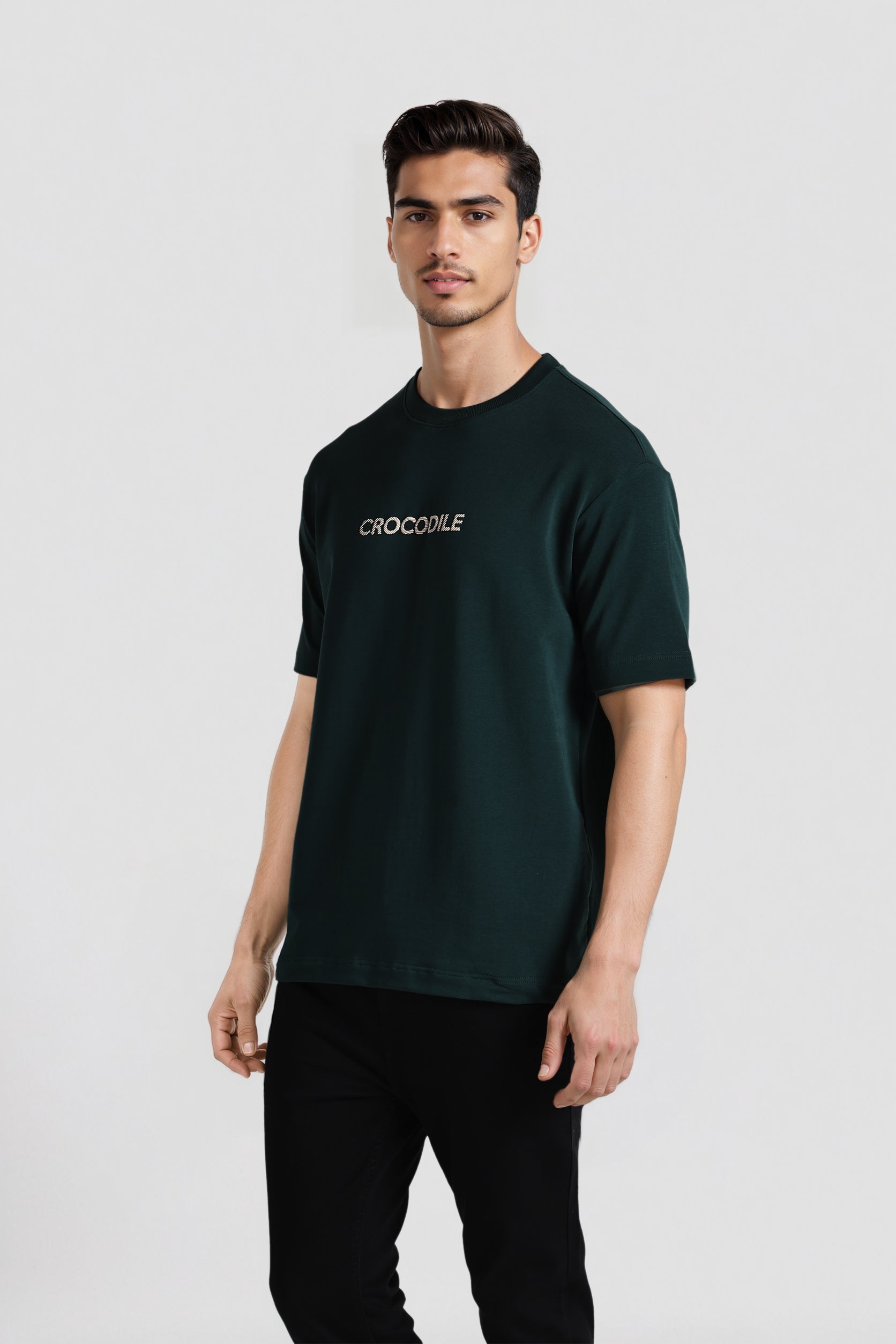 Man wearing a dark green t-shirt with 'Crocodile' logo on a white background